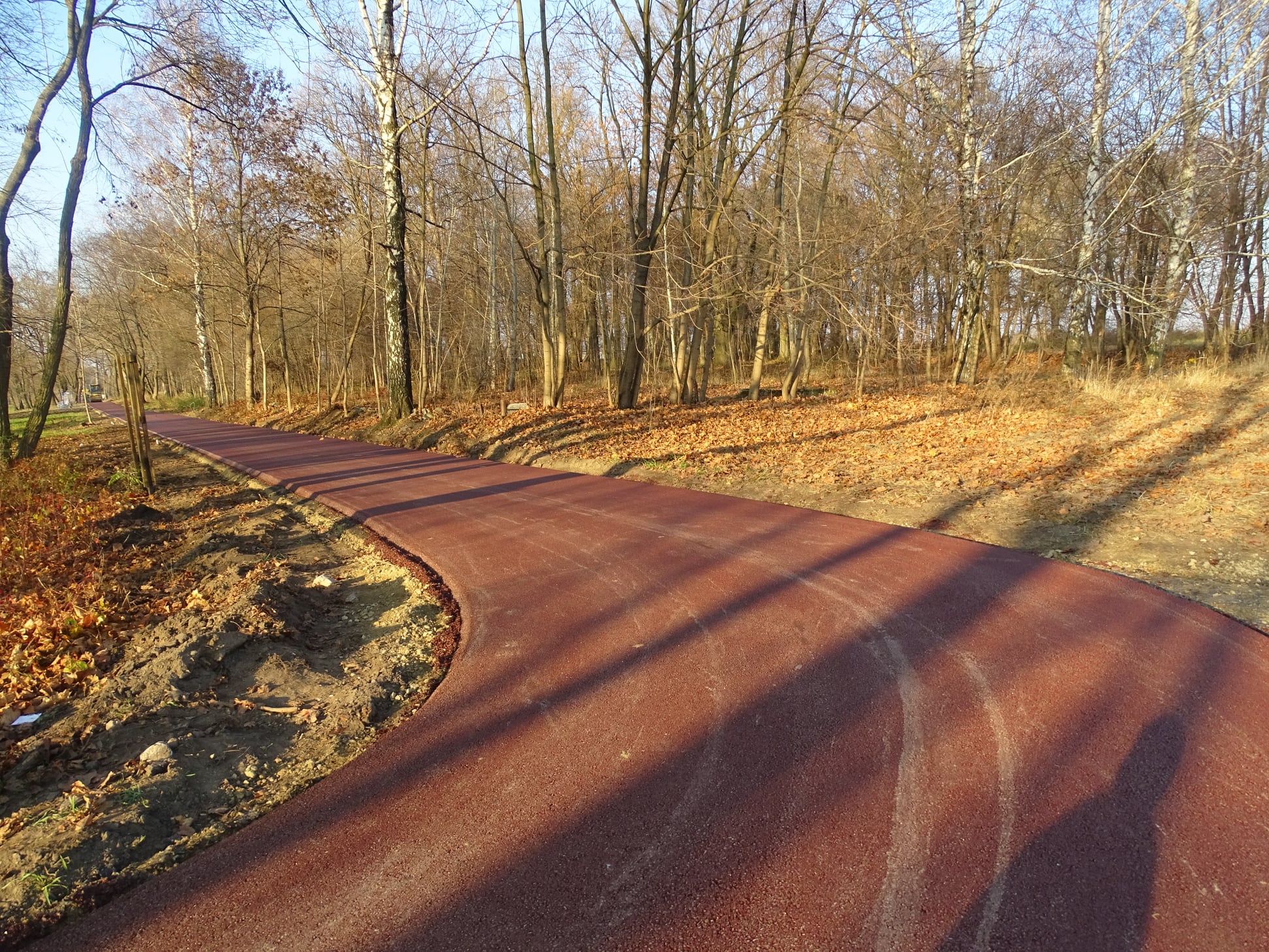 Zdjęcie ścieżki nad zalewem, wykonanej z czerwonego asfaltu.