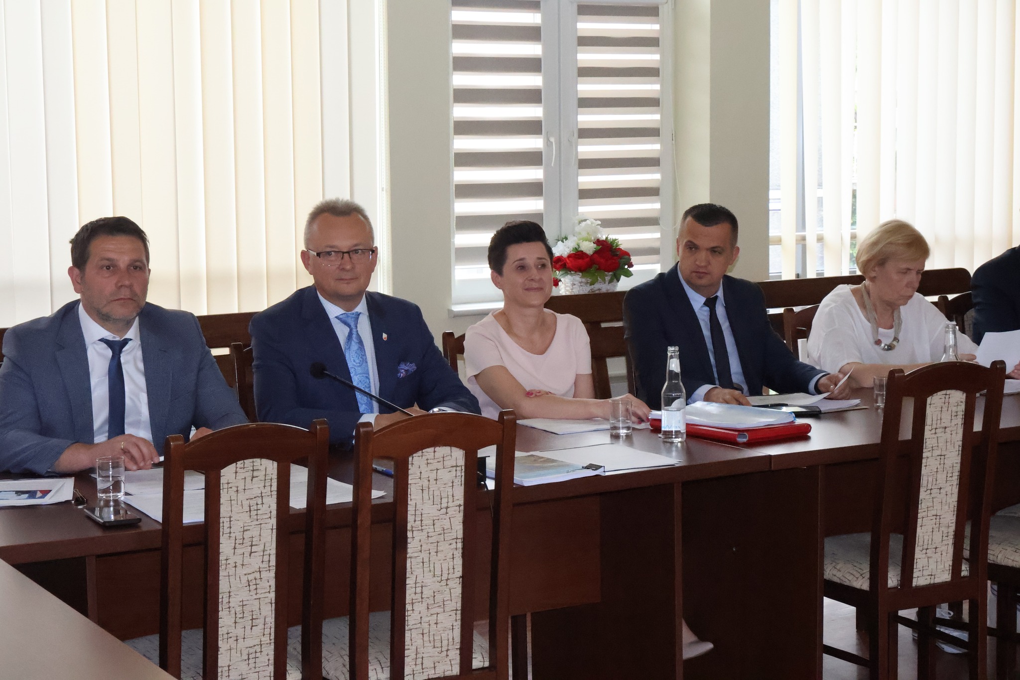 Na zdjęciu znajduje się 5 osób, w tym 3 mężczyzn i 2 kobiety. Wszyscy siedzą przy stole. 