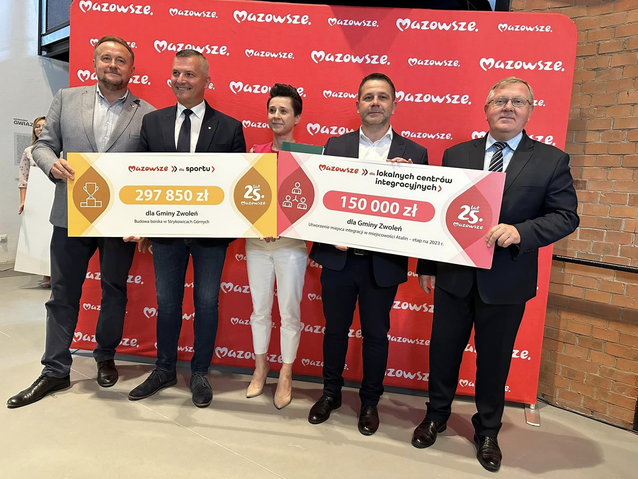 Pamiątkowa fotografia wykonana po podpisaniu umowy z symbolicznymi czekami.