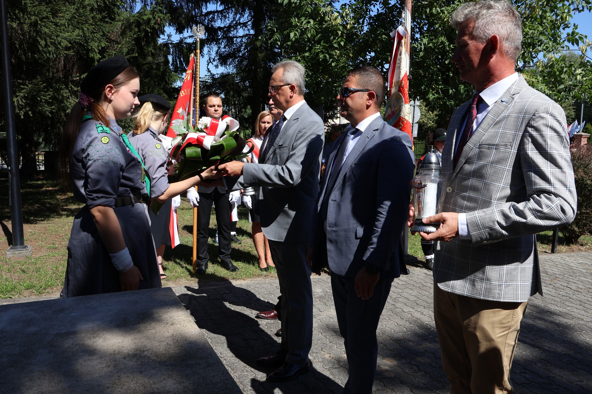 Kwiaty pod pomnikiem Nieznanego Żołnierza złożyli przedstawiciele gminy Zwoleń, delegacja składa się z 4 mężczyzn, jeden z nich w rękach trzyma kwiaty