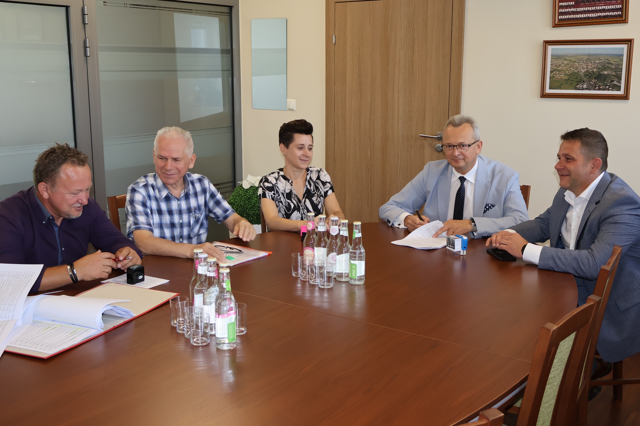 Na zdjęciu znajduje się 5 osób, w tym jedna kobieta. Wszyscy siedzą przy dużym brązowym stole. 